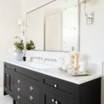 A gorgeous black bathroom vanity sits on maze marble floor tiles .