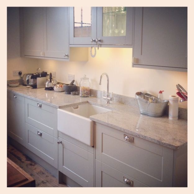 Painted light grey wood kitchen with marble worktops and wood .