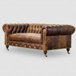 Distressed brown leather chesterfield sofa with caster legs .
