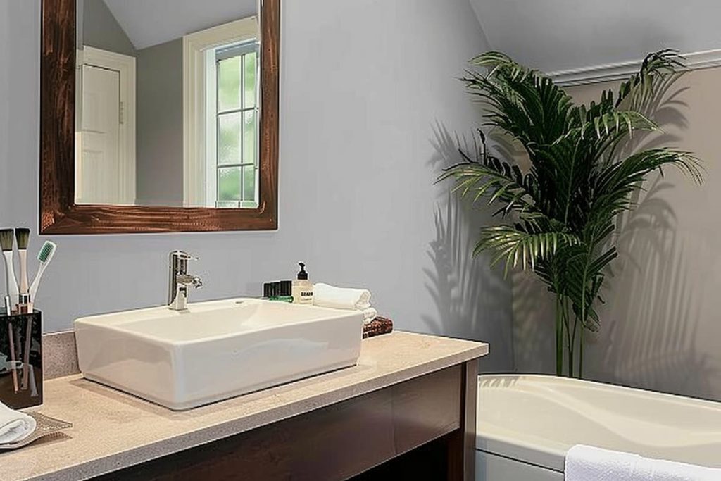 a realistic picture of a powder room with a sink, a wall mirror for the face, a large potted plant next to it, toiletries and tissue paper on the shelves, the walls are painted with pebble gray paint