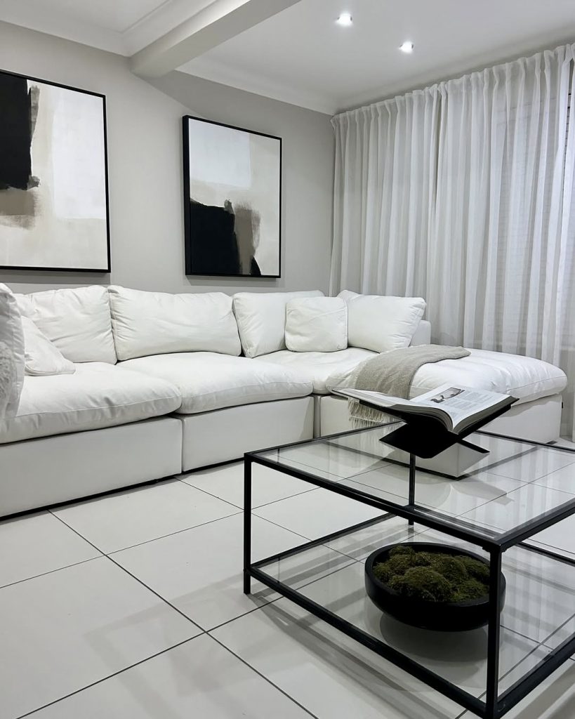 White sectional sofa with black and glass coffee table in monochrome room