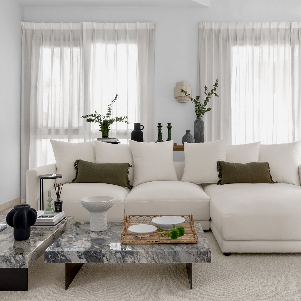 White sectional sofa with olive green pillows and marble table