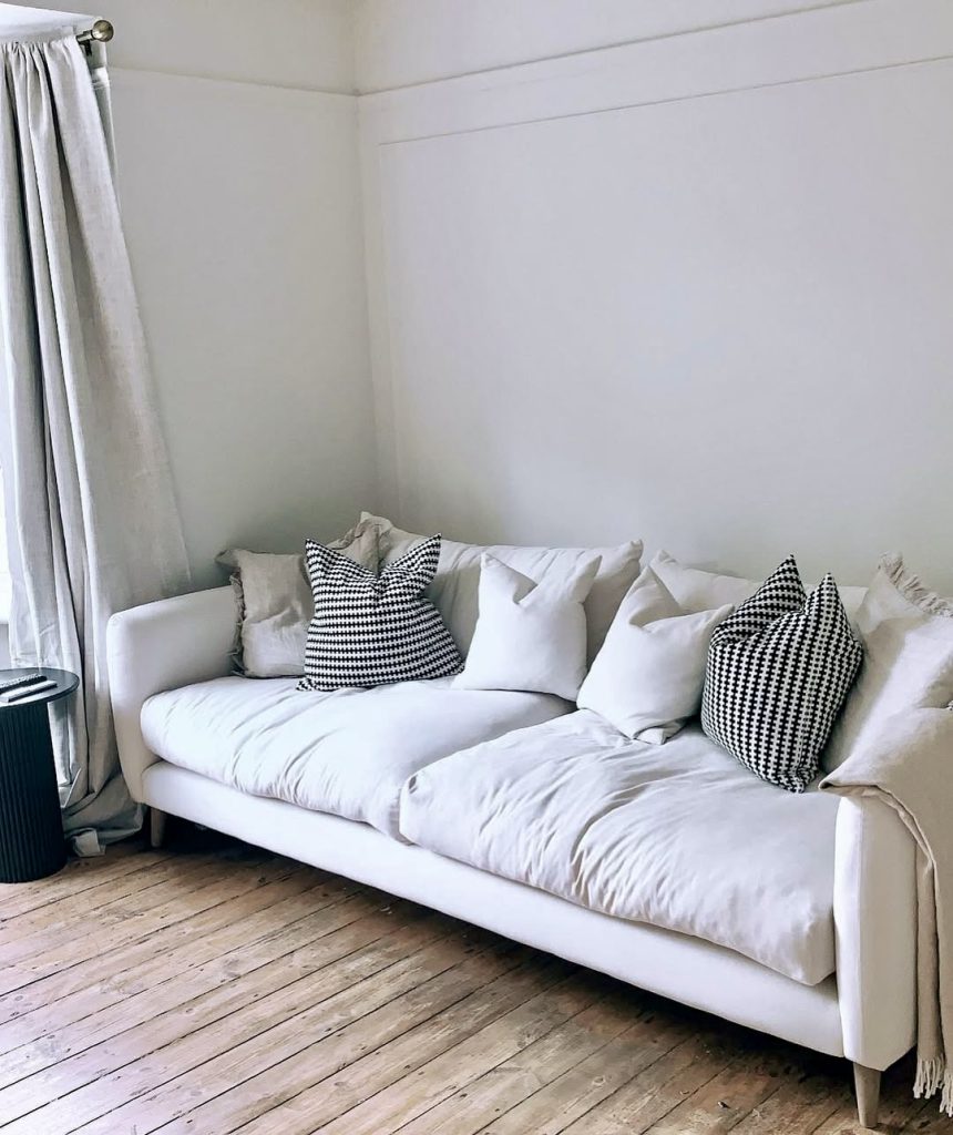 White sofa with houndstooth pillows and natural wood floor