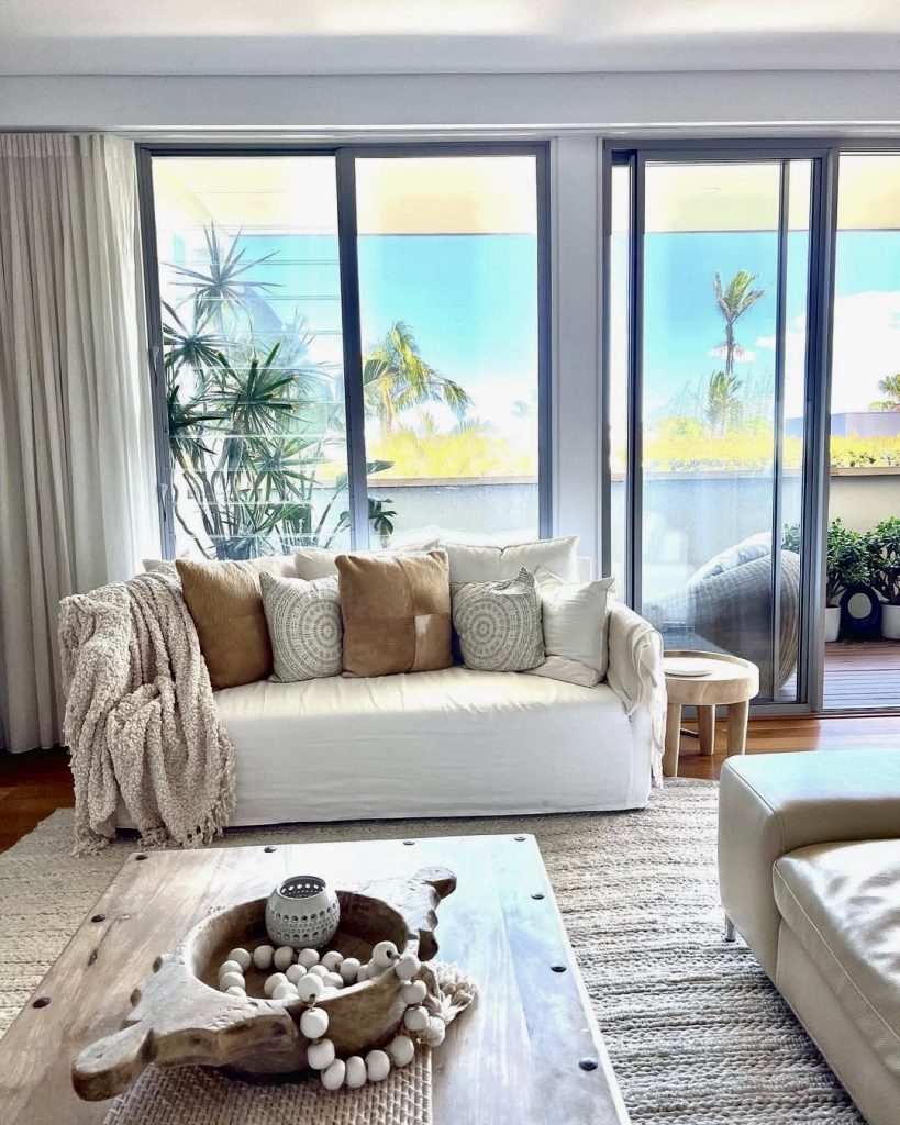 White sofa with sand and clay colored cushions in coastal living room