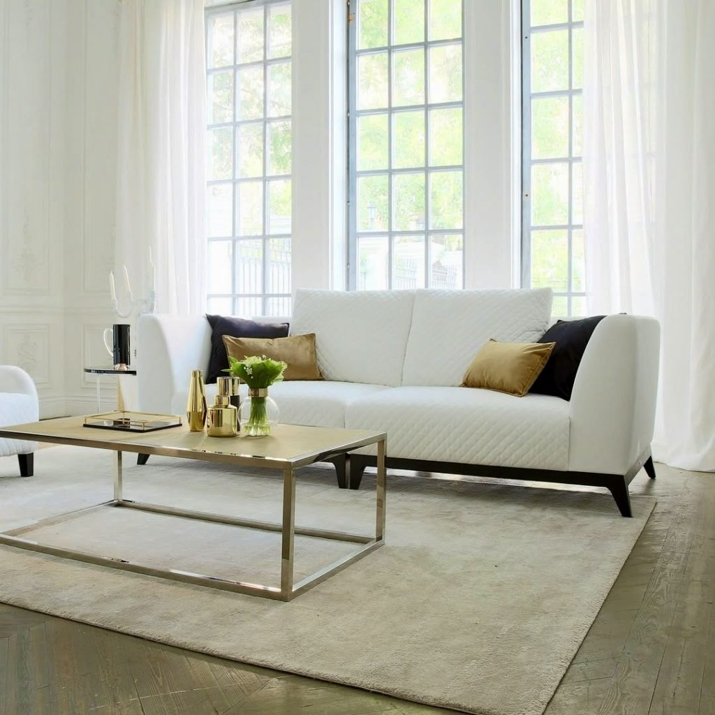 White sofa with velvet pillows and black legs in elegant room