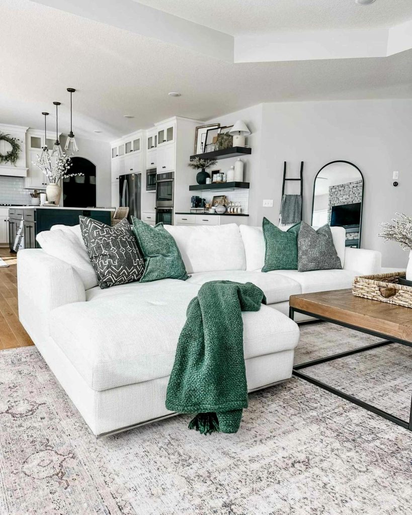 White sectional sofa with emerald green pillows and distressed rug