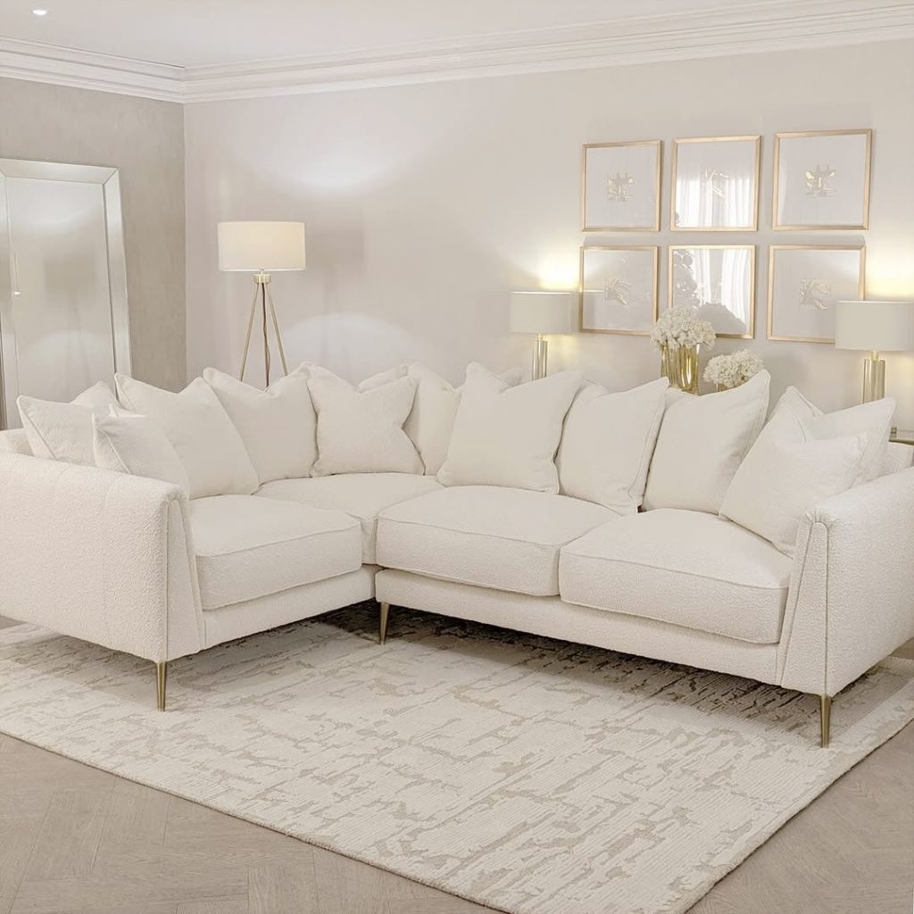 White boucle sofa with gold legs and pale pillows