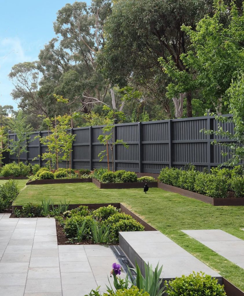 Deep charcoal fence in structured garden