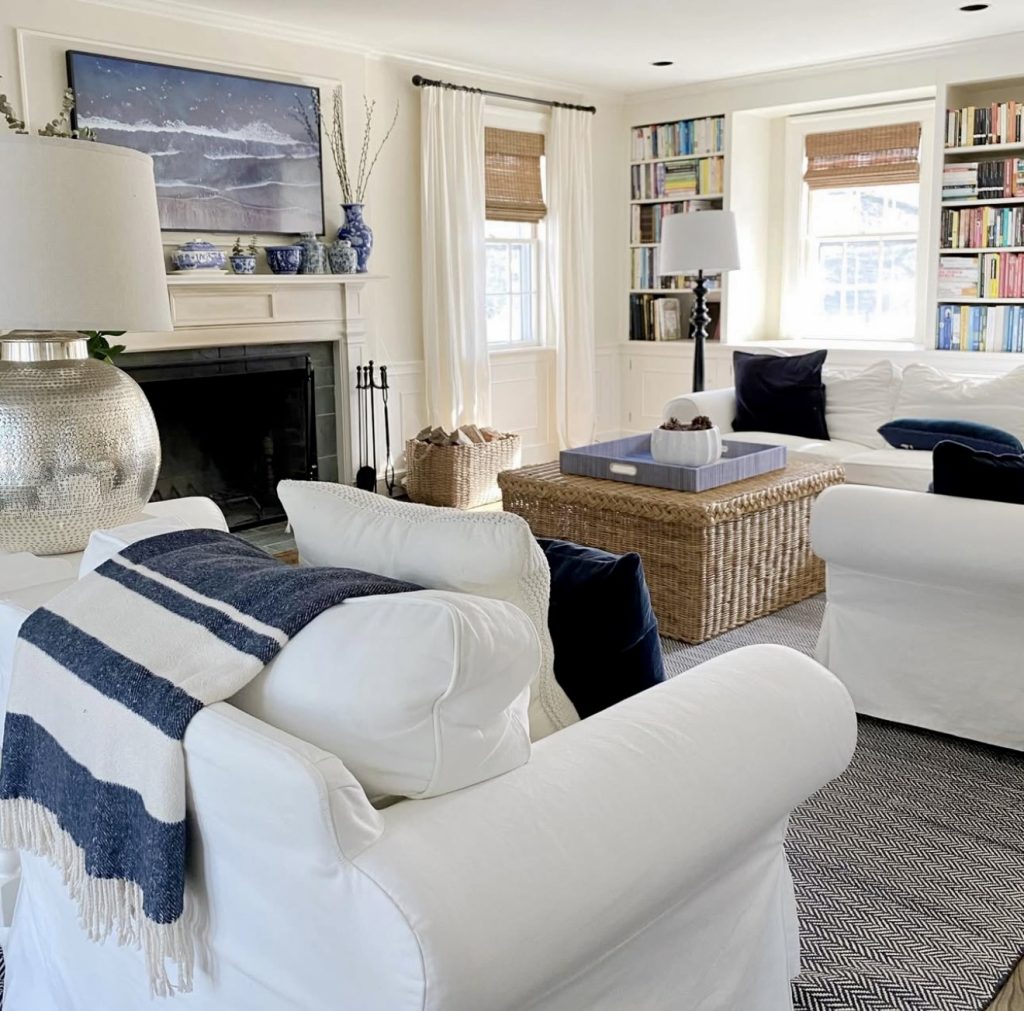 White slipcovered chairs with navy pillows and rattan coffee table