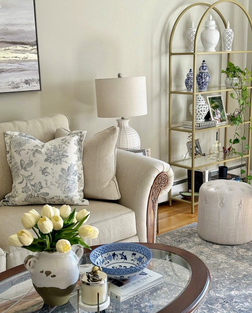Beige sofa with floral pillow and gold arched shelf
