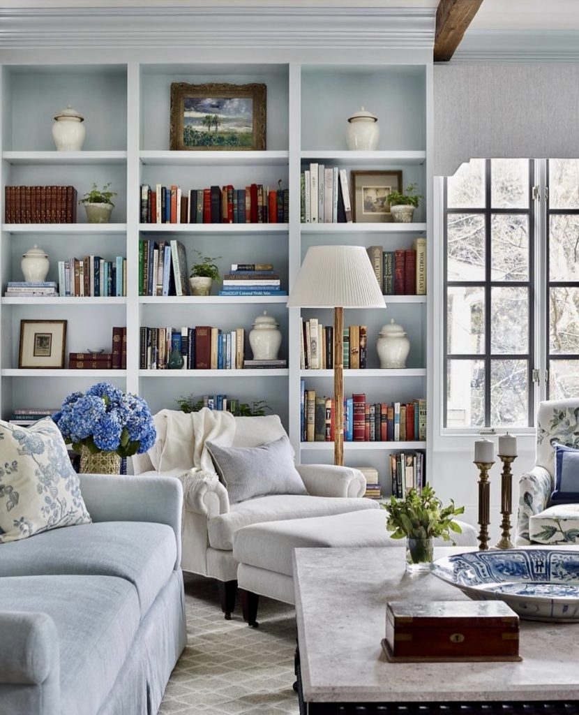 Built-in blue bookcases with cream armchairs and blue hydrangeas
