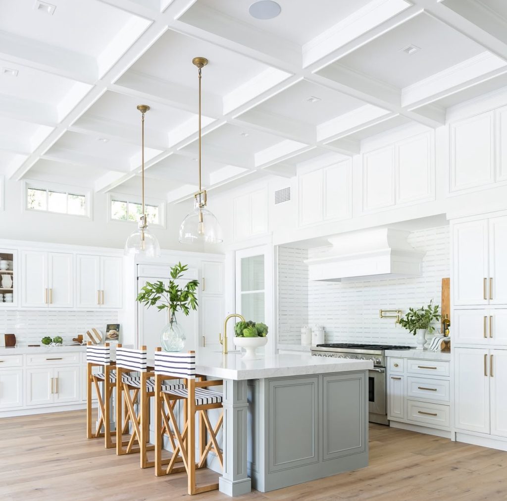 White cabinetry with gray island and striped director chairs