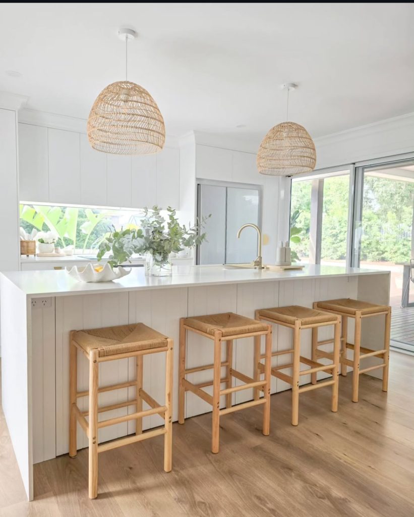 White kitchen island with wood stools and woven pendant lights