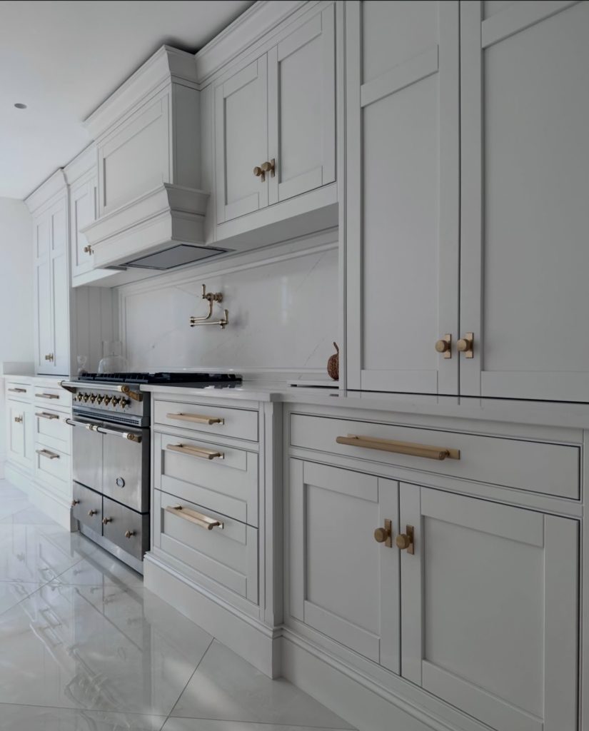White kitchen with brass hardware and gray granite countertops