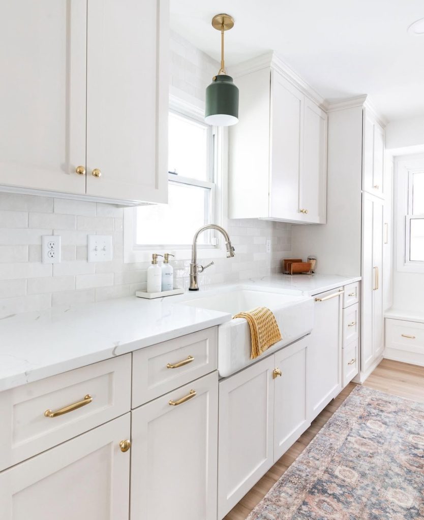 Galley kitchen with white cabinets and green pendant light