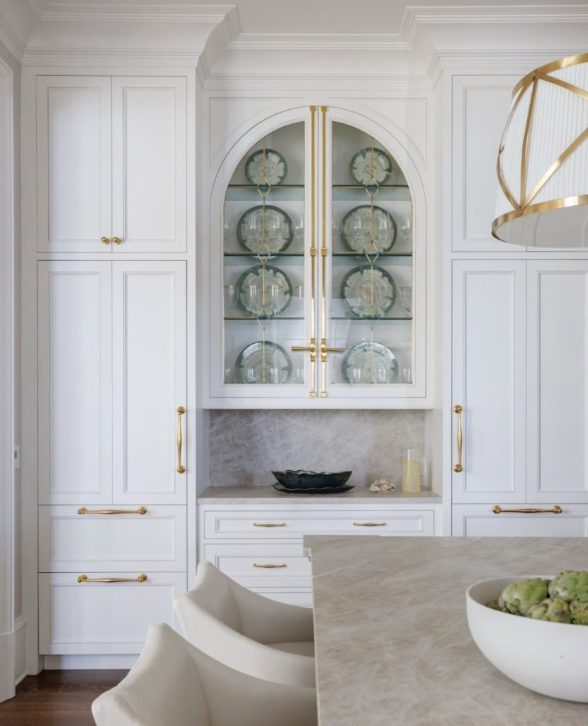 White kitchen with arched glass cabinets and gold hardware