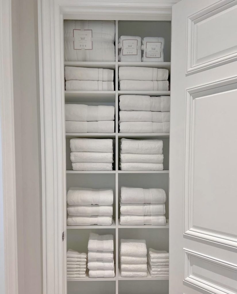 Uniformly stacked white towels in linen closet