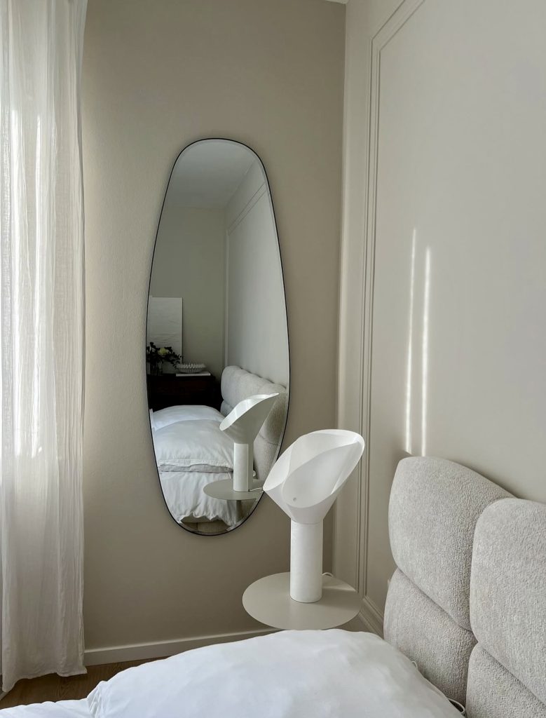 Minimalist bedroom with curved mirror and soft lighting