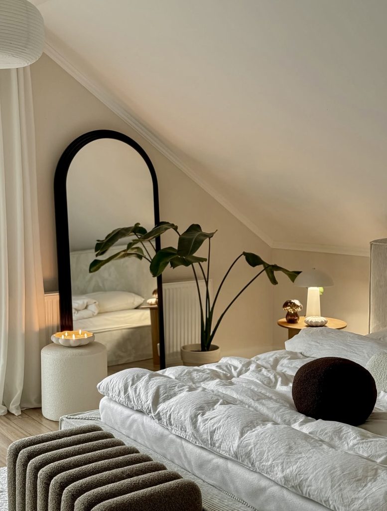 Attic bedroom with arched mirror and greenery