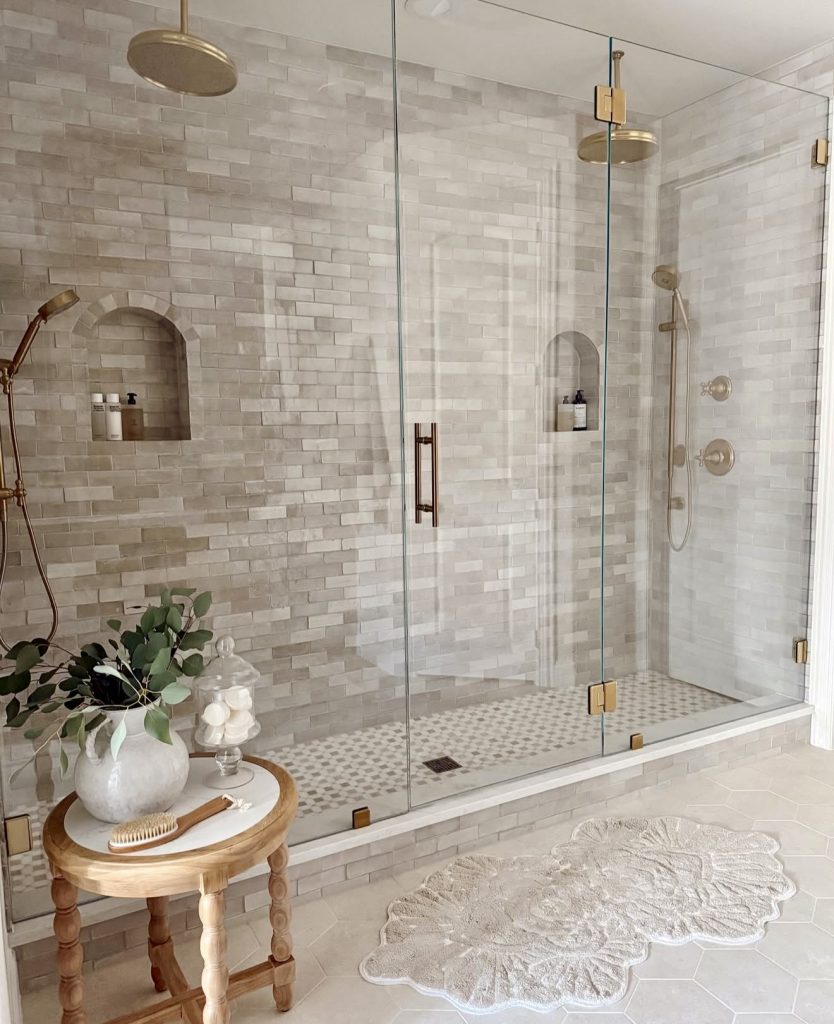 Walk-in shower with gold hardware and stone wall