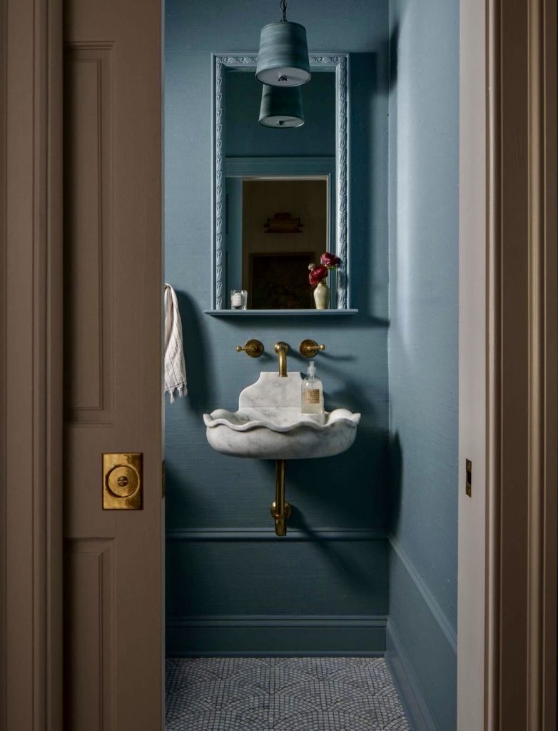 Blue powder room with scalloped marble sink and brass fixtures