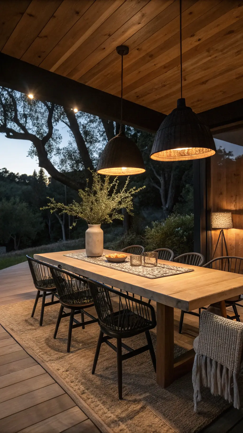 Intimate dining area at dusk with solid oak table, black wooden chairs, oversized matte ceramic pendant light, warm spotlighting on linen table runner, and a simple vase.