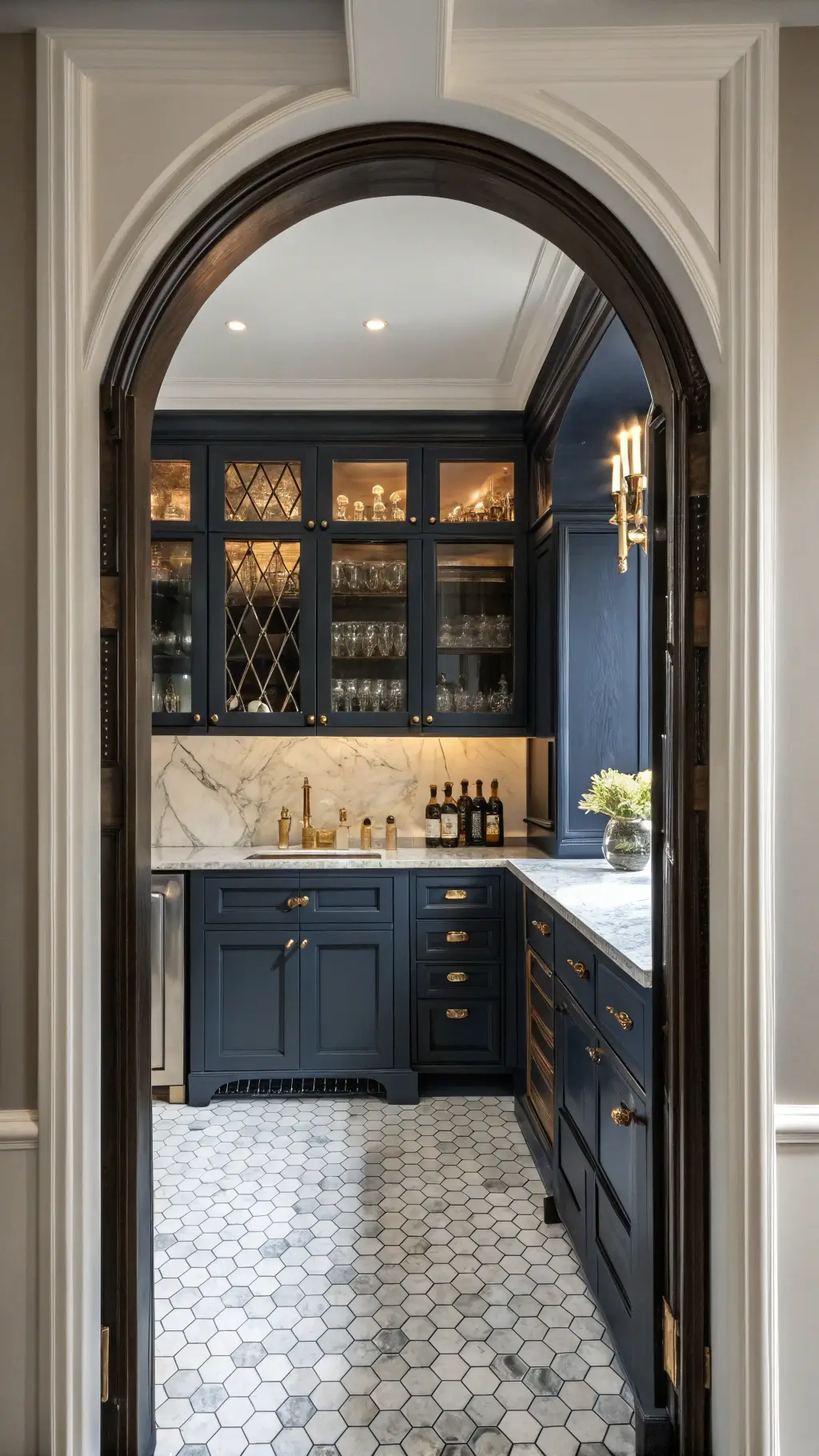 moody butler's pantry with dark navy cabinets, antique mirror inserts, custom wine storage, marble countertop, brass gallery rails, vintage decanters, etched glass details, hexagonal floor tiles