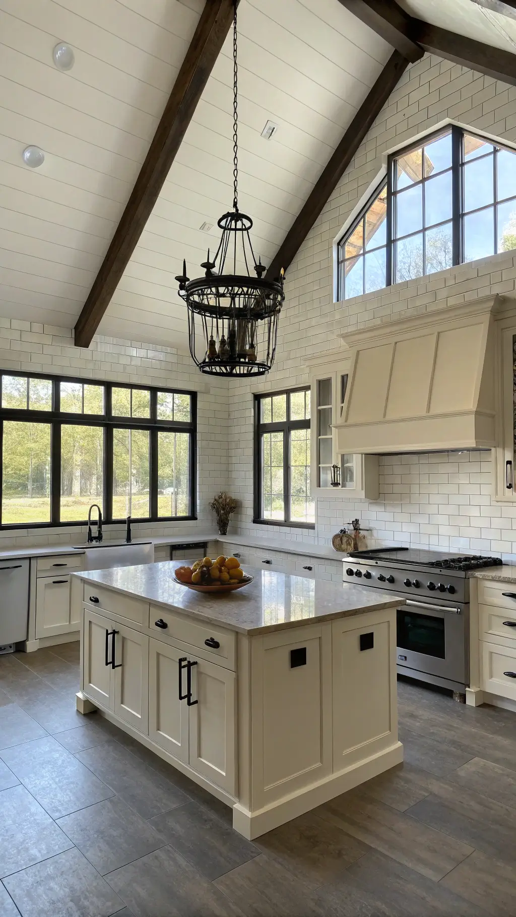Sunlit modern farmhouse kitchen with cream cabinets, distressed wood island, concrete countertop, white subway tile backsplash, and exposed ceiling beams. Vintage iron chandelier adds character.