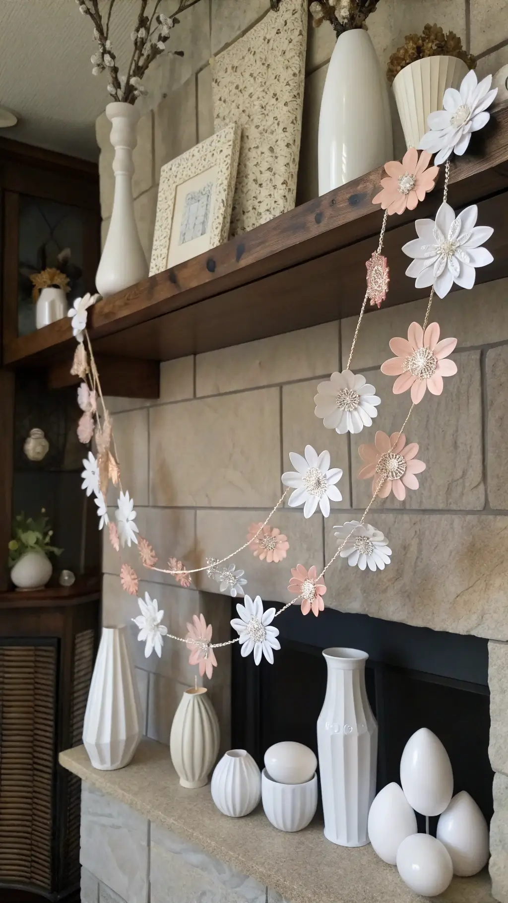 Sunlit modern great room with floating shelves showcasing ceramic vessels and matte geometric eggs, complemented by white and blush paper flower garland
