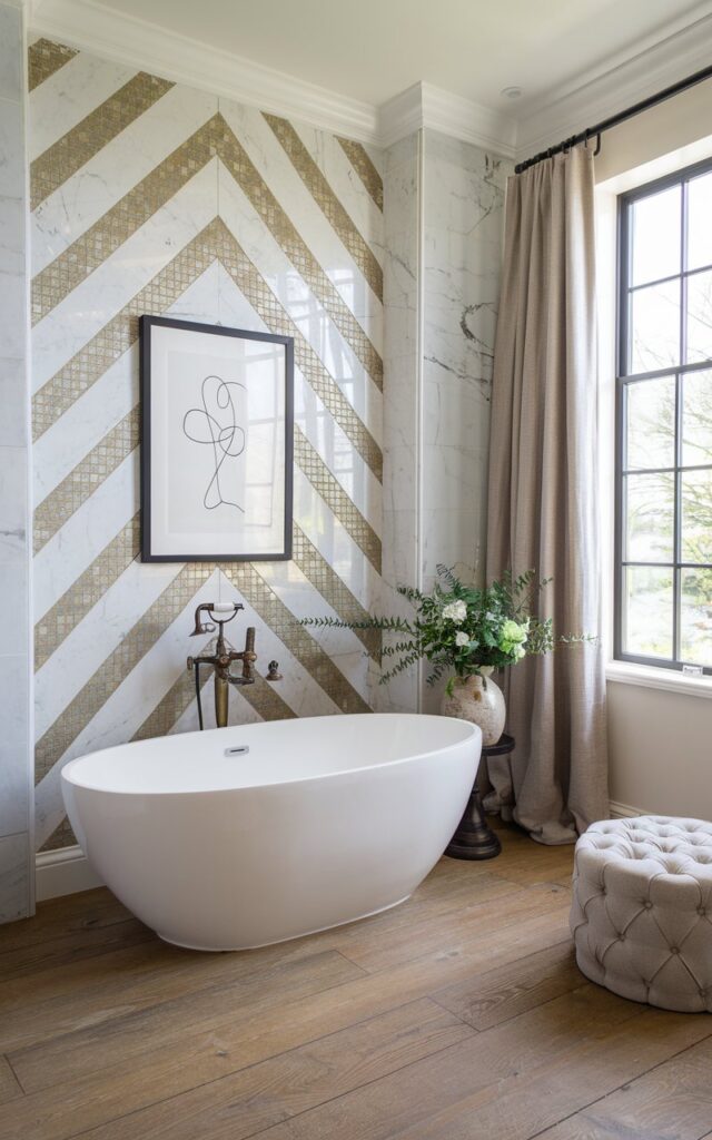 A photo of a luxurious modern English countryside bathroom with a striking accent wall behind a freestanding bathtub. The wall features a herringbone pattern made from a mix of white marble and gold-accented mosaic tiles, creating a refined yet opulent focal point. A minimalist black-and-white line art print in a thin black frame hangs centered above the tub. The freestanding tub is oval and matte white, sitting on wide-plank oak flooring. Soft natural light filters through a large paned window with linen curtains. Add vintage brass fixtures, a tufted ottoman, and fresh greenery in a ceramic vase for an elegant countryside touch.
