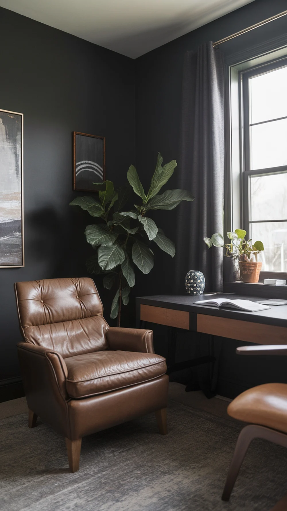 A moody home office with charcoal gray walls, a brown leather chair, and plants.