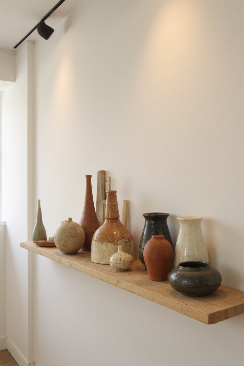 end of hallway decor - Artful Ceramic Displays to Enliven Your Hallway - Light wood shelf with ceramic vessels...