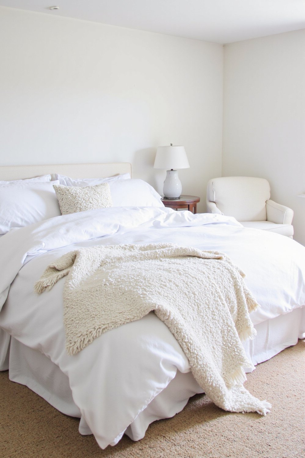 White bedroom decor ideas - Inviting White Bedroom: Rich Textures and Layered Bedding - Cozy white bedroom with plush textiles