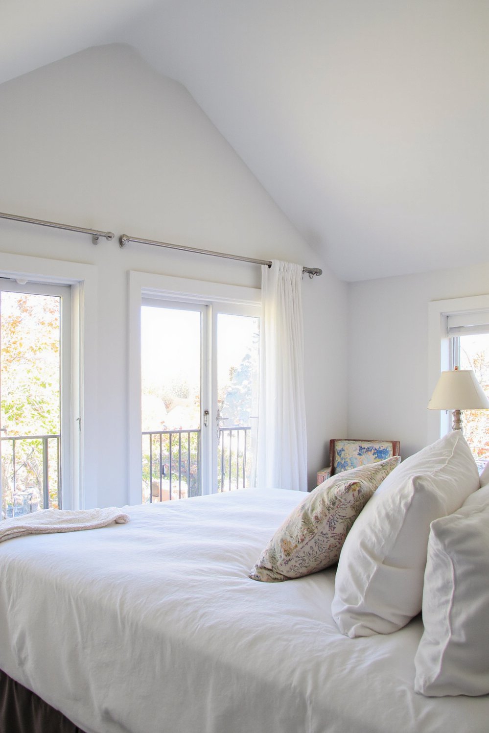 White bedroom decor ideas - Light-Filled White Bedroom: Embracing Airiness and Height - Bright white bedroom with floor-to-ceiling windows