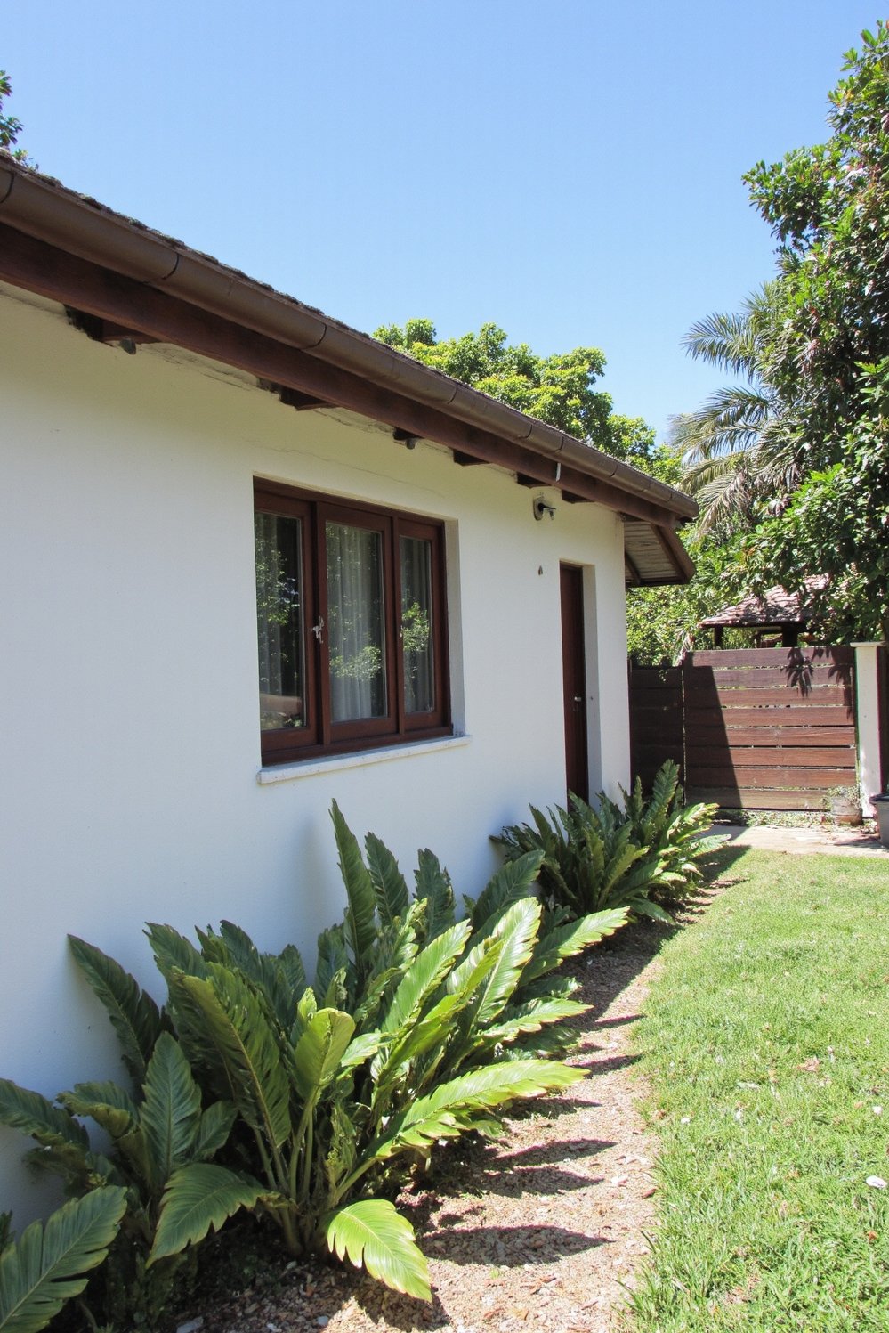 tropical house design ideas - Minimalist Tropical Residence: Whitewashed Facades and Streamlined Landscaping