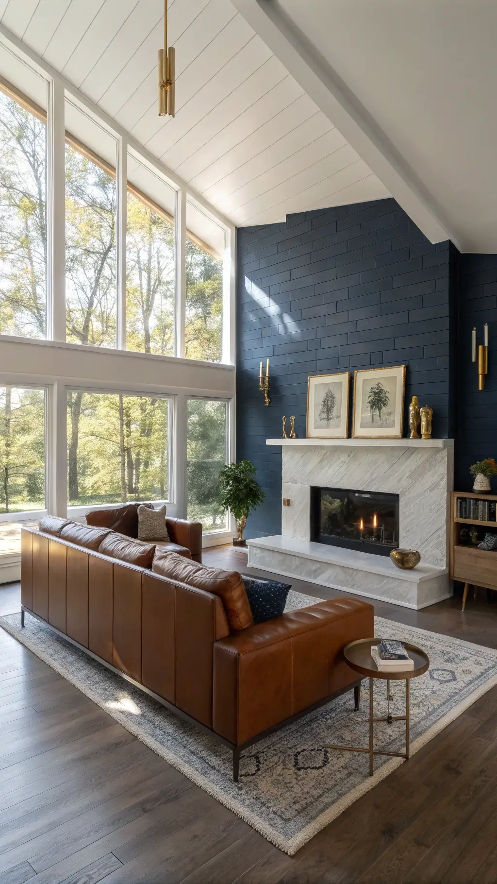 Elegant modern living room featuring a navy blue corner fireplace, mid-century leather sofa, white oak mantel, brass-framed artwork, and vintage brass candlesticks illuminated by sunlight through tall windows.